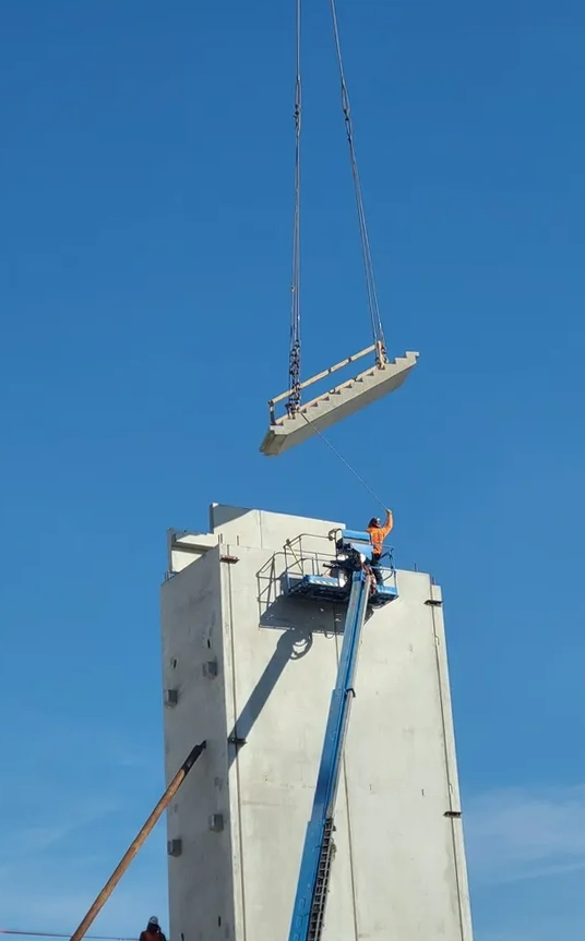 Crane lifting hollow core concrete panels installed by Concrete Erectors, Inc. on a precast project in the United States
