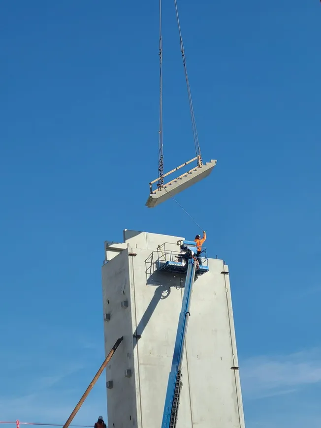 Precast erector guiding a concrete panel into position during high-rise precast erection