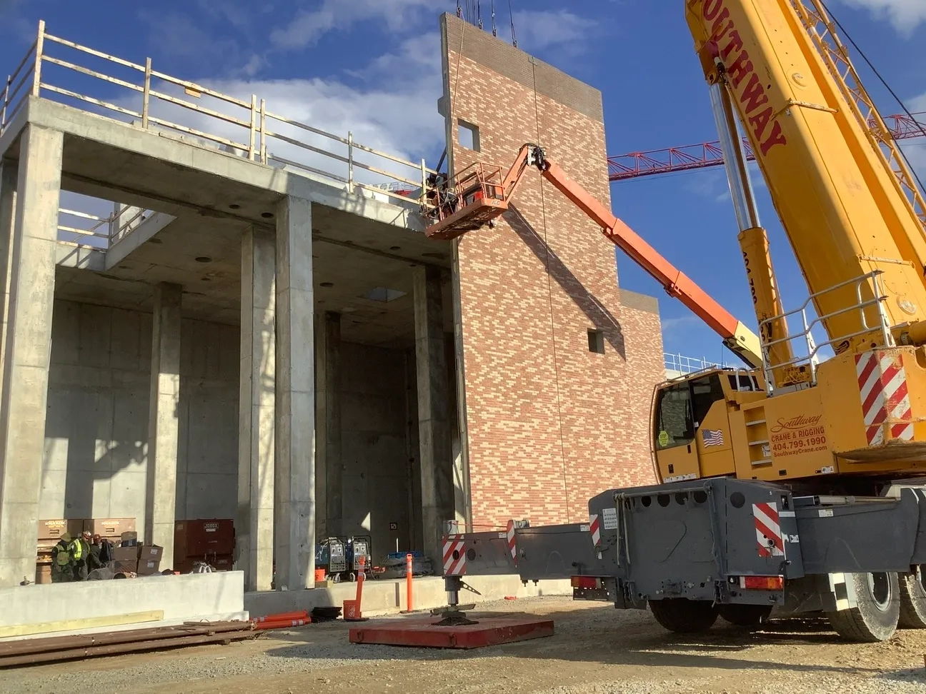 Crane lifting precast concrete beams during structural erection by Concrete Erectors, Inc