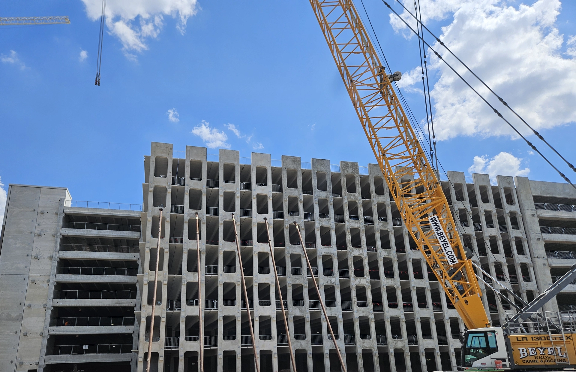 Precast erector installing structural concrete panels on multi-level parking garage project